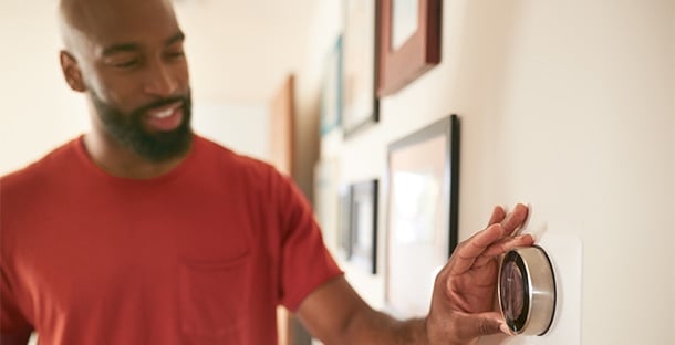 A man changes the temperature on the thermostat.