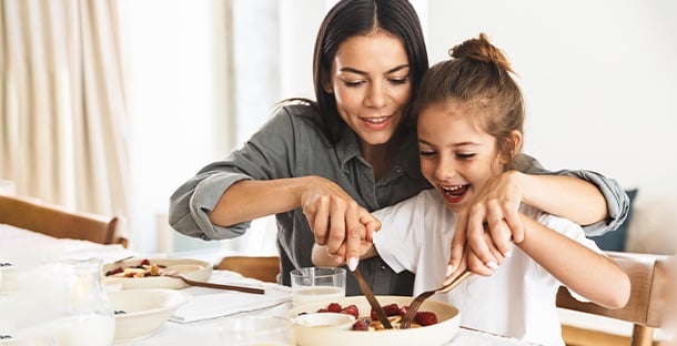 A mother helping cut her daughter's food.