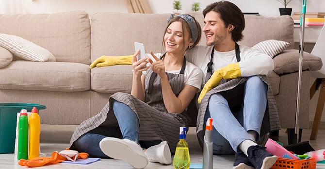 A couple taking a break from cleaning and looking at their smartphone