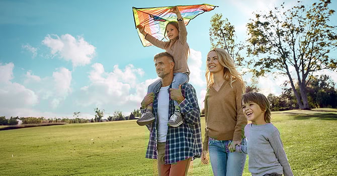 A happy family fly a kite in the park.