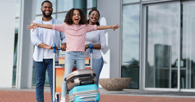 A happy family with luggage outside a modern building.