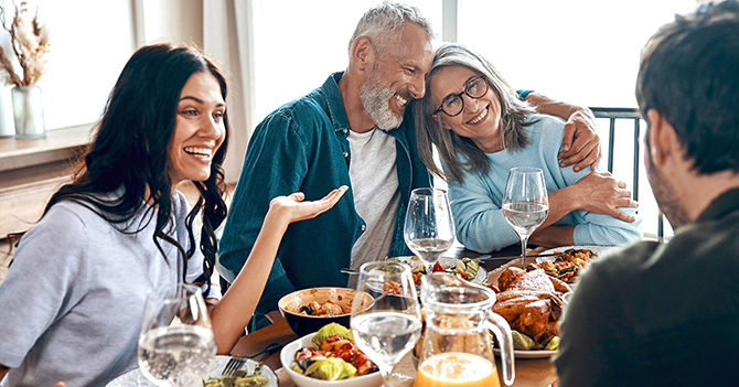 A diverse group of people chat and laugh over a homemade dinner.