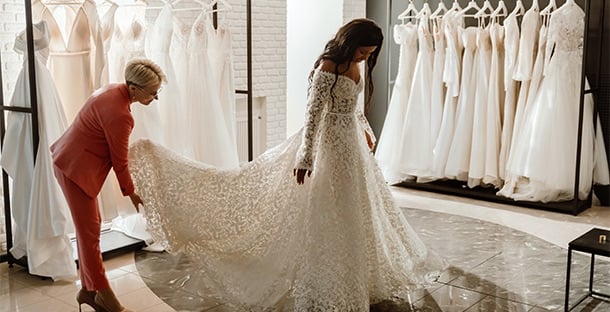 A woman in a wedding dress getting it altered inside the store.