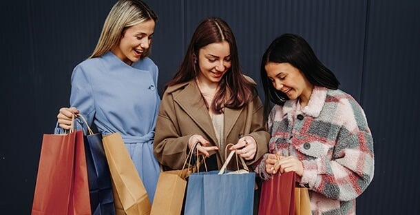 A group of friends holding shopping bags and smiling.