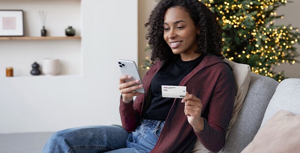 A woman shops on her phone with her USALLIANCE Credit card.