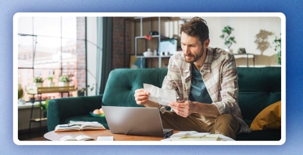 A man reviews his finances in his living room.