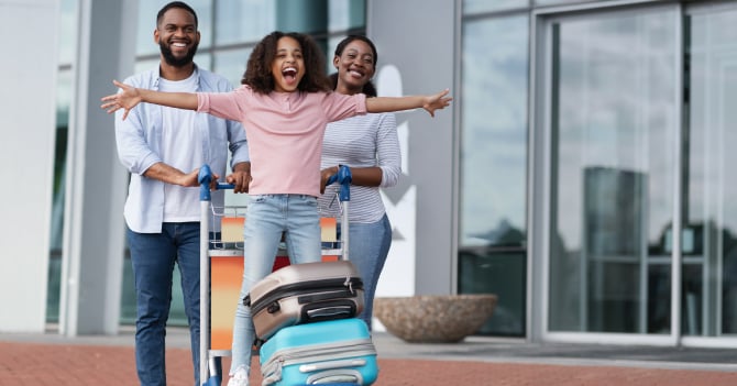 A happy family with luggage outside a modern building.